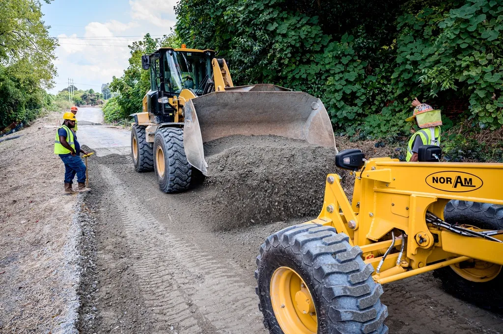 A loader spreading and levelling granular material on a graded site